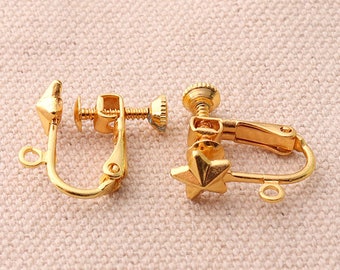 May include: A pair of gold-tone clip-on earring findings with a star-shaped design on one side and a pointed design on the other.
