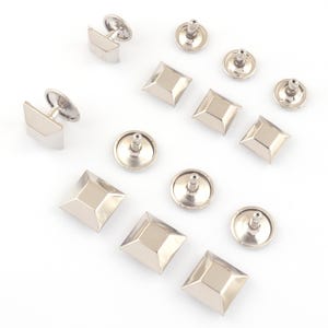 May include: A set of silver-toned metal pyramid-shaped studs with a flat back. The studs are designed for use in leather crafting and other DIY projects.