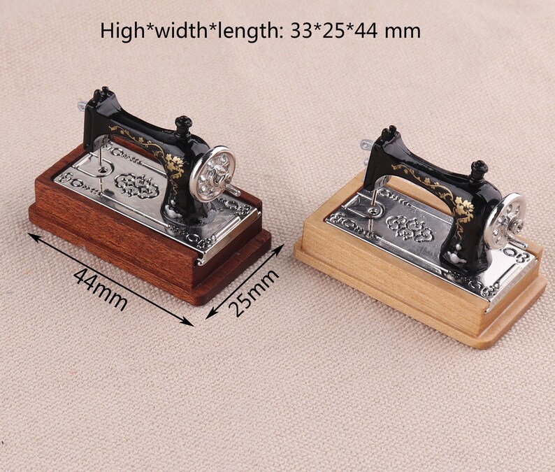 May include: Two miniature black sewing machines with gold accents on wooden bases. The sewing machines are 33 mm high, 25 mm wide, and 44 mm long.