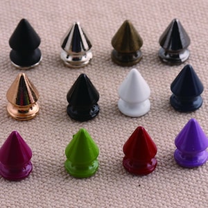 Può includere: Assortimento di 12 borchie piramidali in metallo di vari colori, tra cui nero, bianco, oro, argento, verde, rosso, viola e marrone. Le borchie sono alte circa 2,5 cm e hanno una punta appuntita.