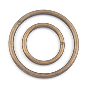 May include: Two gold-toned metal rings, one inside the other. The larger ring is slightly wider than the smaller ring.