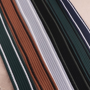 May include: Assortment of striped fabric trim in various colours, including brown, grey, green, and black. Each trim features a white stripe running along the edge.