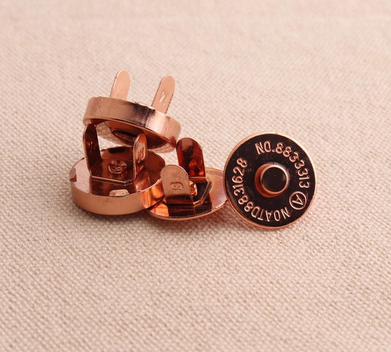 May include: Four rose gold magnetic snap closures with the text "NOATD8391628 NO.883313" on one of the closures.