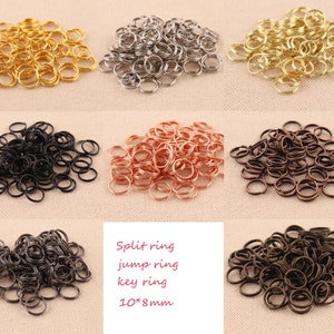 Könnte beinhalten: Eine Auswahl an Splintringe in verschiedenen Farben und Ausführungen, darunter Gold, Silber, Schwarz, Kupfer und Bronze. Die Ringe haben einen Durchmesser von 10 mm und eine Breite von 8 mm. Splintringe, Sprungringe, Schlüsselringe.