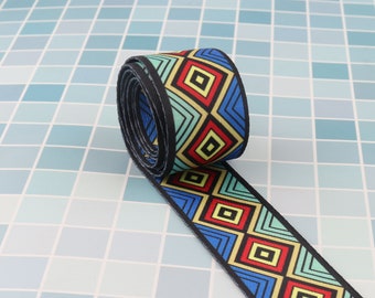 May include: A rolled up blue, green, red, and yellow patterned ribbon with a black edge. The ribbon has a geometric design with squares and triangles.