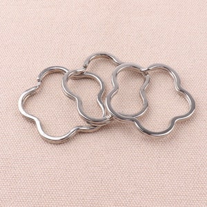 May include: Three silver-toned metal keychains shaped like a four-leaf clover.