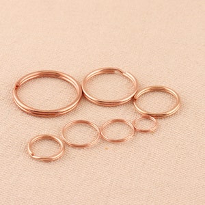 Può includere: Un set di sette portachiavi in oro rosa di diverse dimensioni. I portachiavi sono disposti in fila dal più grande al più piccolo.