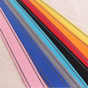May include: A variety of colorful webbing with reflective strips. The webbing is arranged in a rainbow pattern, with pink, blue, gray, turquoise, black, red, orange, and yellow.