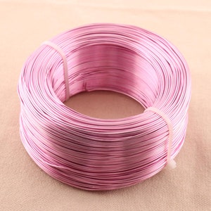 Op de afbeelding: Een spoel met roze aluminiumdraad. De draad is strak om de spoel gewikkeld, waardoor een glad, egaal oppervlak ontstaat.