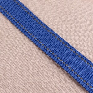 May include: A close-up of a blue and gray striped ribbon. The ribbon is woven with a textured pattern and has a subtle sheen.