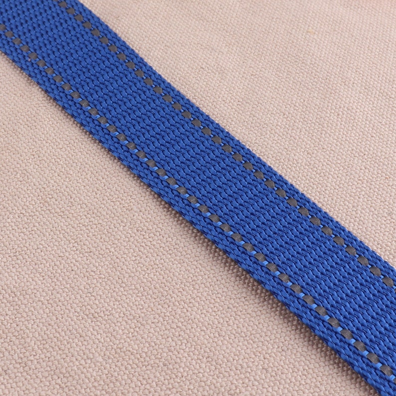 May include: A close-up of a blue and gray striped ribbon. The ribbon is woven with a textured pattern and has a subtle sheen.
