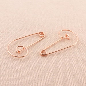 以下が含まれることがあります： ユニークな湾曲したデザインのゴールドトーンの安全ピン2本。ピンは金属製で、光沢のある仕上げになっています。