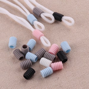 May include: Assortment of colorful silicone cord stoppers in pink, blue, gray, and black. The stoppers are designed to keep cords from fraying and are perfect for use with earbud cords, charging cables, and other types of cords.