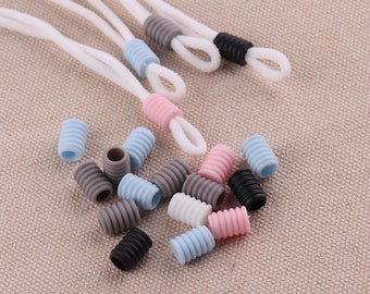 May include: Assortment of colorful silicone cord stoppers in pink, blue, gray, and black. The stoppers are designed to keep cords from fraying and are perfect for use with earbud cords, charging cables, and other types of cords.