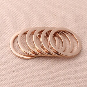 May include: A set of eight gold-toned metal rings, stacked and overlapping. The rings are smooth and have a polished finish.