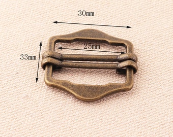 May include: Antique brass buckle with two slots for a strap. The buckle measures 30mm wide, 33mm high, and 25mm between the slots.