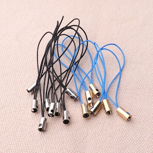 May include: A set of 15 black and blue string phone charms with silver and gold metal caps. The charms are tied together in a bundle.