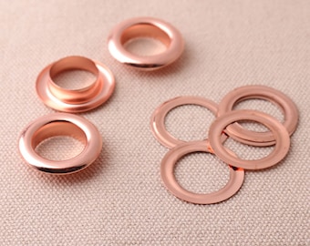 May include: A set of rose gold eyelets for crafts and DIY projects. The eyelets are in two sizes, with the larger eyelets having a raised lip.