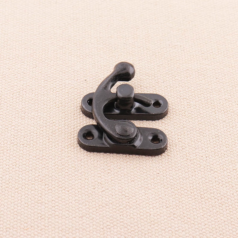 May include: Black metal latch with a curved handle and two mounting holes. The latch is designed to secure a box, door, or other object.