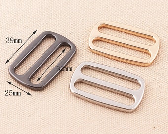 May include: Three metal slider buckles in different finishes: black, gold, and silver. The black buckle is 39 mm long and 32 mm wide. The buckles are 25 mm wide.
