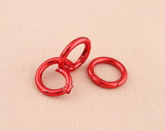 Può includere: Tre portachiavi in metallo rosso con chiusura a molla. I portachiavi sono impilati uno sopra l'altro.