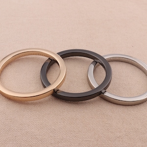 May include: Three metal rings, one gold, one black, and one silver, are interlocked. The rings are smooth and shiny.