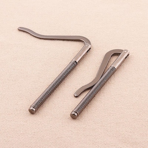Op de afbeelding: Twee zilveren metalen geldclips met een veerontwerp. De clips zijn gebogen en hebben een gladde afwerking.
