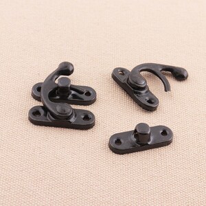May include: Three black metal clasps with a hook and loop design. The clasps are used for fastening fabric or leather.
