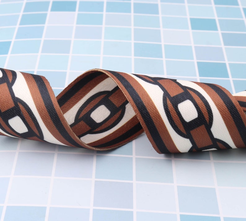May include: Brown and white striped ribbon with a chain link pattern. The ribbon is curled and has a textured surface.