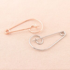 以下が含まれることがあります： 円形のデザインの安全ピンが2つ。1つはシルバー、もう1つはローズゴールドです。