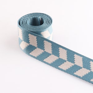 May include: A blue and white patterned webbing strap. The strap is woven with a checkered pattern.