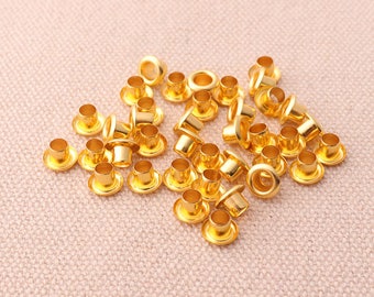 May include: A pile of gold-colored metal eyelets, used for reinforcing holes in fabric or leather.
