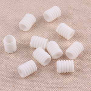 May include: Ten white plastic cord stoppers with a ribbed texture. The stoppers are designed to keep cords from fraying.