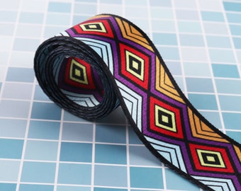 May include: A colorful woven ribbon with a geometric pattern of diamonds in shades of blue, red, yellow, and purple. The ribbon is rolled up and has a black edge.