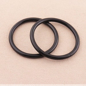 May include: Two black metal rings, probably for attaching to a bag or purse.