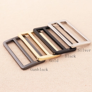 May include: Four metal belt buckle sliders in different finishes: gunmetal, gold, black, and silver.