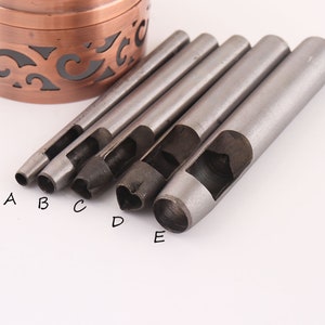 May include: Five metal leather hole punch tools with different shaped cutouts. The tools are labeled A through E.