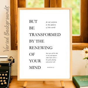 May include: A framed print with the text "BUT BE TRANSFORMED BY THE RENEWING OF YOUR MIND" in black font. The print is displayed on a wooden easel. The text includes a quote from Romans 12:2.