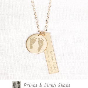 May include: Gold necklace with a round pendant featuring two tiny footprints and a rectangular bar pendant with the text "Serena Wiley 8AM 7lbs 2oz 04.29.21".