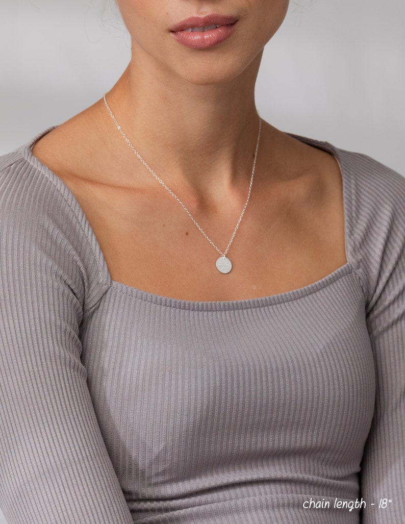 May include: A silver chain necklace with a small, round pendant. The chain is 18 inches long.