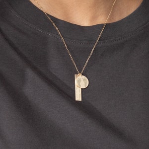 May include: Gold necklace with a small round pendant featuring a footprint design and a bar pendant with the text "the world is yours to explore". The chain is 18 inches long.