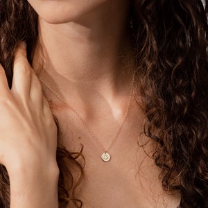 May include: A gold necklace with a small, round pendant featuring a paw print design. The chain is 18 inches long.
