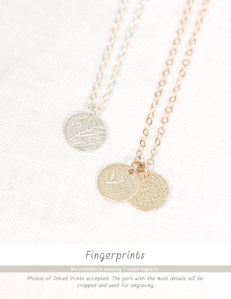 Puede incluir: Dos collares de plata con colgantes redondos que presentan dise&ntilde;os de huellas dactilares. Los colgantes est&aacute;n sobre un fondo blanco.