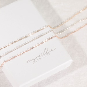 May include: Three delicate gold chains in different shades of gold, including rose gold, yellow gold, and white gold, are displayed on a white box with the text "mymille jewellery".