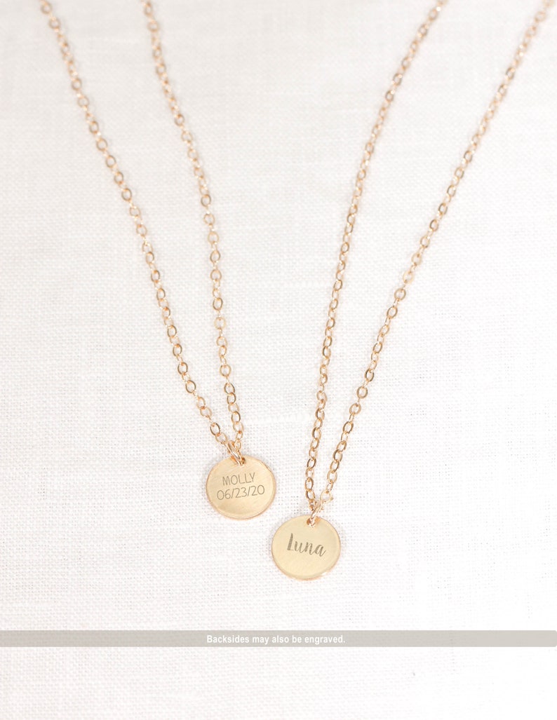 May include: Two gold necklaces with round pendants. The pendant on the left says "Molly 06/23/20". The pendant on the right says "Luna".