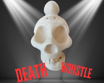 Op de afbeelding: Een witte fluit in de vorm van een schedel met de rode woorden "DEATH WHISTLE". De fluit heeft grote oogkassen en een prominente kaak. De achtergrond is donkergrijs met twee schijnwerpers die op de fluit schijnen.