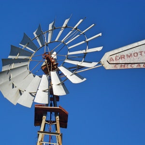 May include: A white windmill with a red Aermotor Chicago sign. The windmill has a large, round base and many blades.