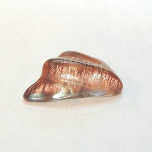 Oregon sunstone with a Schiller effect, this rare fancy-cut carved gem weighs 6.34 carats and measures 10x18 mm