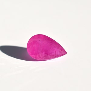 May include: A pear-shaped pink gemstone with a faceted cut.