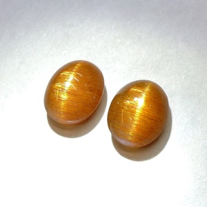 Golden copper to orange oval cat's eye sunstone, this pair of 7x9 mm calibrated feldspar weighs 3.97 carats